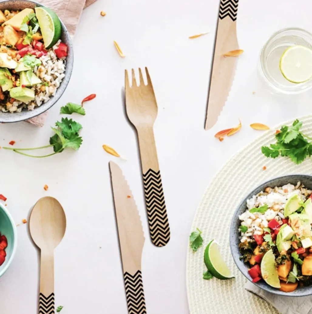 Black chevron birchwood fork, knife and spoon laid around grain bowls on a table